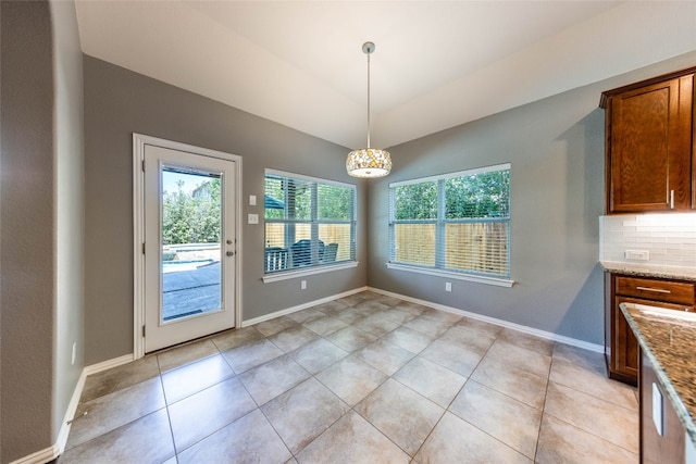 unfurnished dining area with an inviting chandelier, light tile patterned flooring, and vaulted ceiling