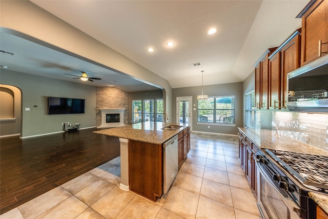 kitchen featuring hanging light fixtures, stainless steel appliances, lofted ceiling, light hardwood / wood-style flooring, and a center island with sink