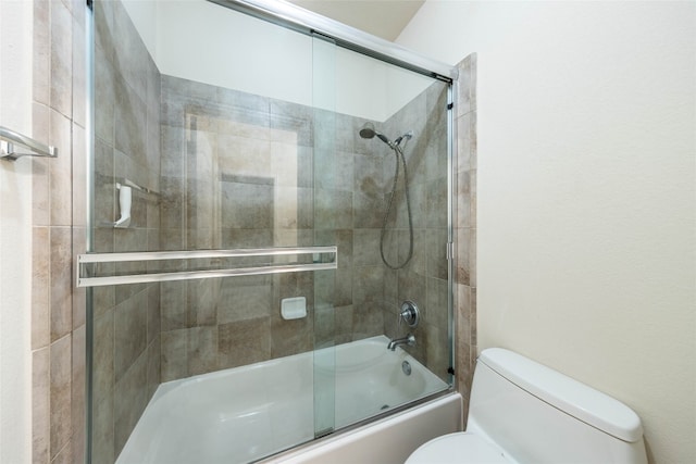 bathroom featuring toilet and bath / shower combo with glass door