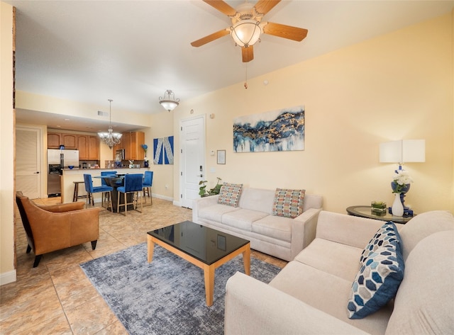 tiled living room with ceiling fan with notable chandelier