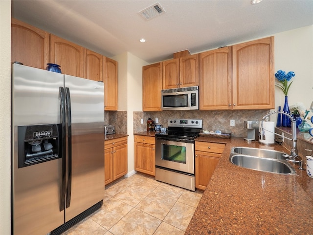 kitchen with dark stone countertops, tasteful backsplash, stainless steel appliances, and sink