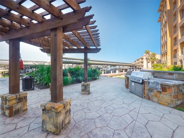 view of patio featuring exterior kitchen, grilling area, and a pergola