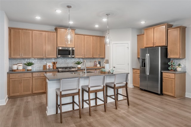 kitchen featuring light hardwood / wood-style flooring, hanging light fixtures, backsplash, sink, and appliances with stainless steel finishes