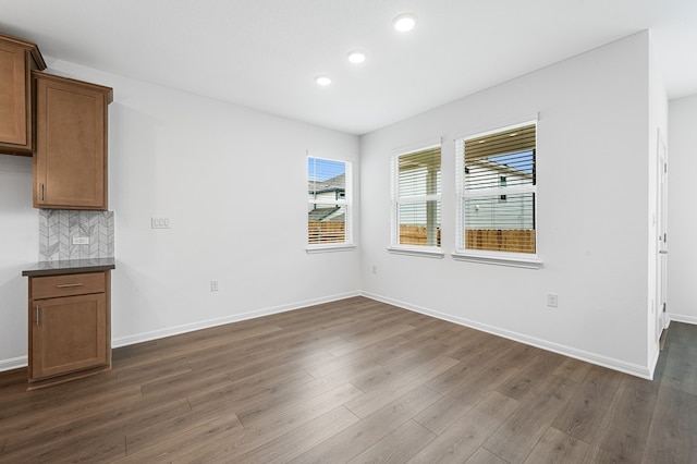 unfurnished dining area with baseboards, recessed lighting, and dark wood-style floors