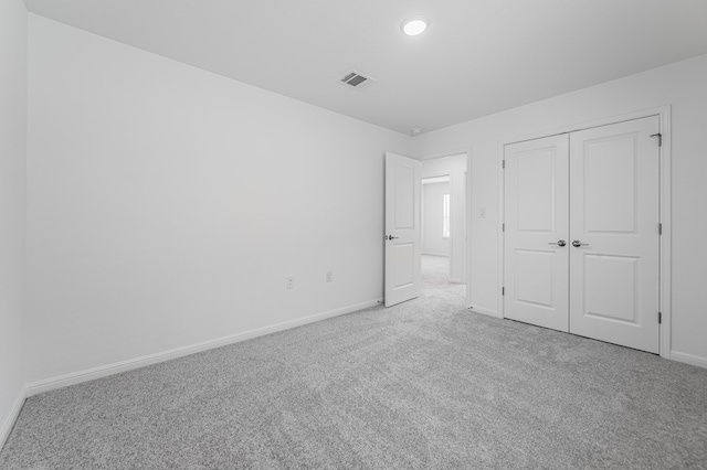 unfurnished bedroom featuring baseboards, carpet, a closet, and visible vents
