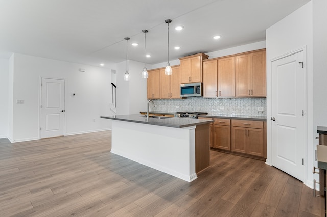 kitchen with a sink, light wood finished floors, recessed lighting, stainless steel microwave, and tasteful backsplash