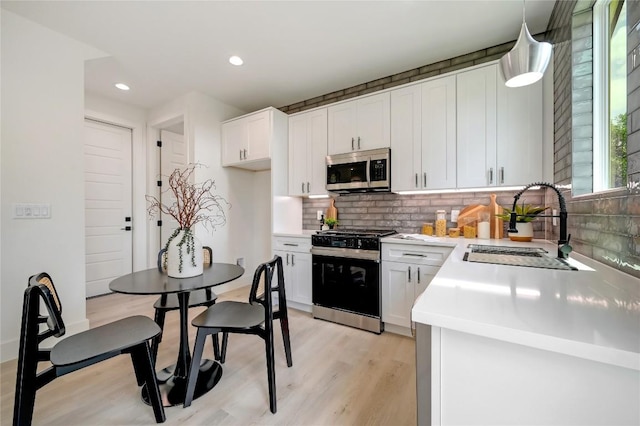 kitchen featuring pendant lighting, white cabinets, stainless steel appliances, and sink