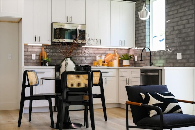 kitchen featuring sink, decorative backsplash, appliances with stainless steel finishes, decorative light fixtures, and white cabinetry