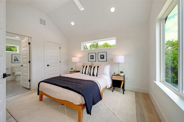 bedroom with lofted ceiling, ensuite bathroom, multiple windows, and light hardwood / wood-style floors