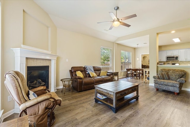 living room featuring ceiling fan, a tile fireplace, and hardwood / wood-style floors