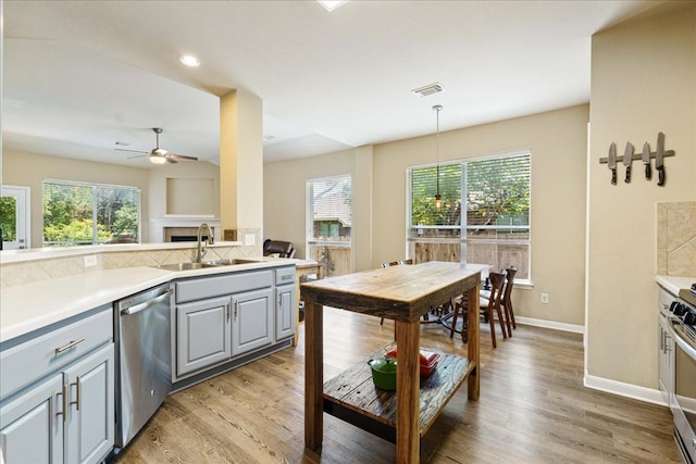 kitchen featuring gray cabinets, decorative light fixtures, a healthy amount of sunlight, and stainless steel dishwasher