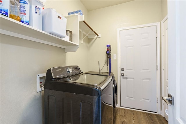 clothes washing area with washing machine and dryer and dark hardwood / wood-style flooring