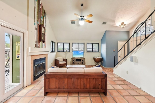 tiled living room with a fireplace, ceiling fan, and a healthy amount of sunlight