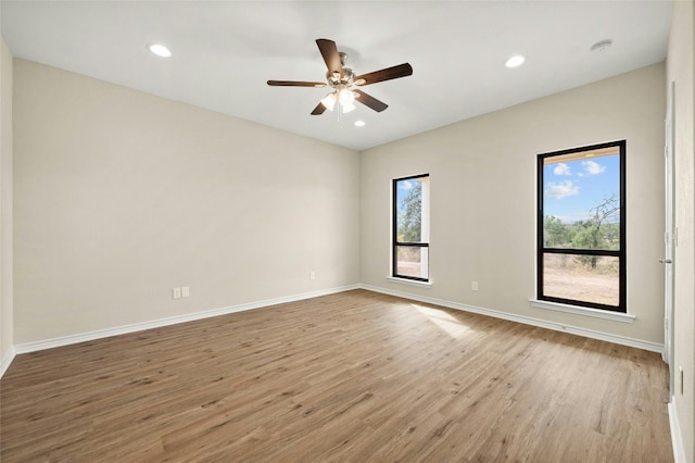 spare room with light hardwood / wood-style flooring, a wealth of natural light, and ceiling fan