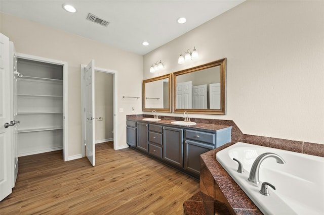 bathroom with a bathing tub, hardwood / wood-style flooring, and vanity