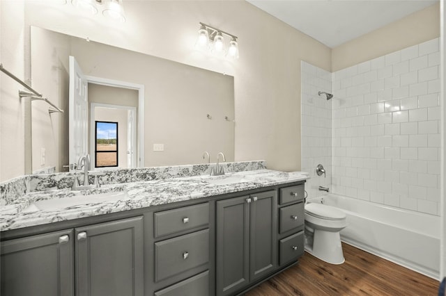 full bathroom with vanity, tiled shower / bath, hardwood / wood-style flooring, and toilet