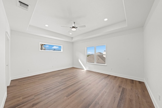 unfurnished room featuring ceiling fan, a raised ceiling, and wood-type flooring