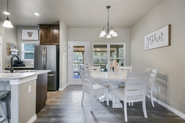 dining space with an inviting chandelier, sink, and dark wood-type flooring