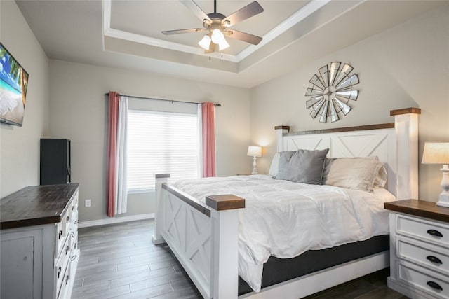 bedroom with dark wood-type flooring, a tray ceiling, and ceiling fan