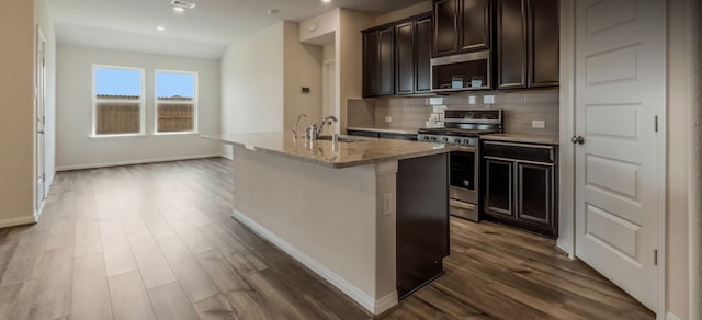 kitchen featuring appliances with stainless steel finishes, dark hardwood / wood-style floors, sink, and a center island with sink