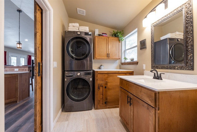 washroom with sink, stacked washer / drying machine, light wood-type flooring, and plenty of natural light