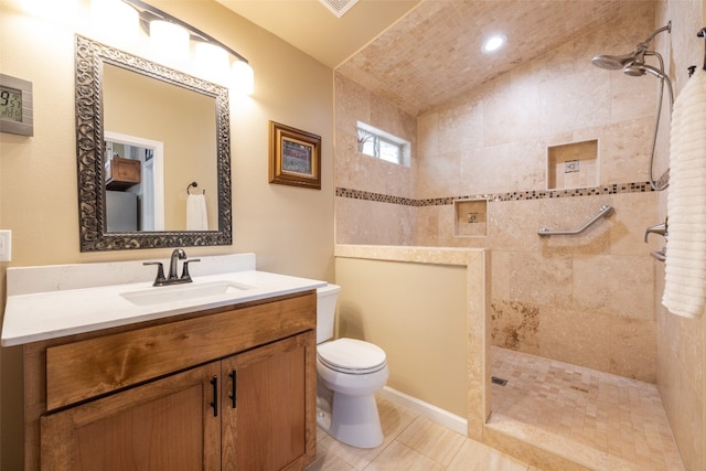 bathroom featuring vanity, toilet, tiled shower, and tile patterned flooring