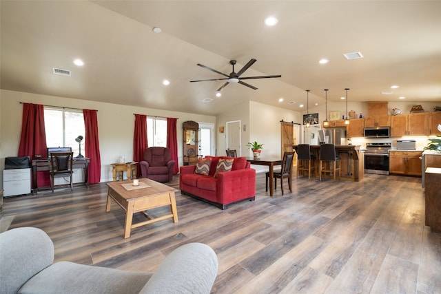 living room featuring a barn door, ceiling fan, vaulted ceiling, and dark hardwood / wood-style flooring