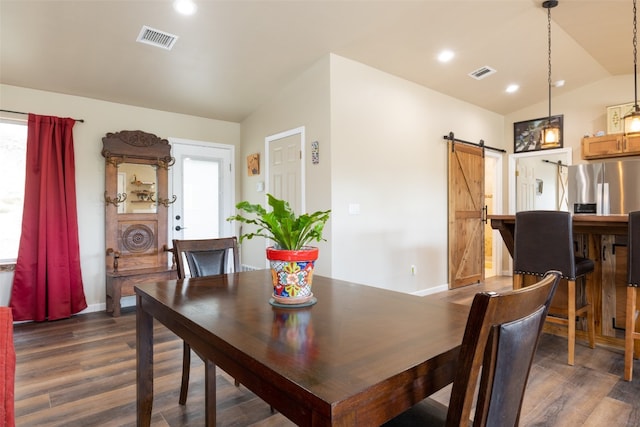 dining room with a barn door, dark wood-type flooring, and vaulted ceiling