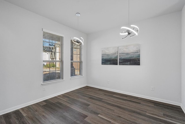 spare room featuring a notable chandelier and dark hardwood / wood-style flooring