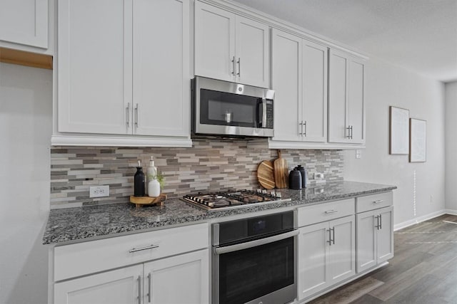 kitchen featuring decorative backsplash, dark stone counters, stainless steel appliances, wood-type flooring, and white cabinets