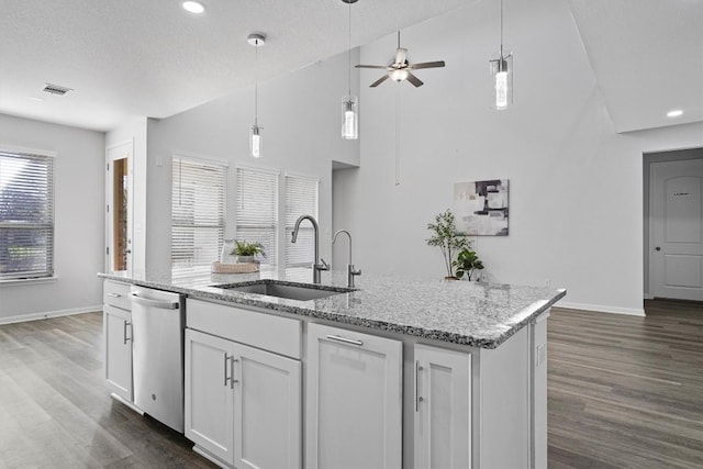 kitchen with light stone counters, stainless steel dishwasher, sink, a center island with sink, and white cabinets