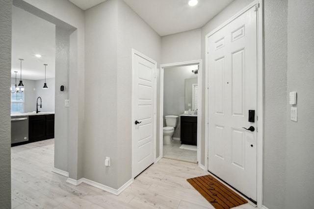 hallway featuring light hardwood / wood-style floors, sink, and a chandelier