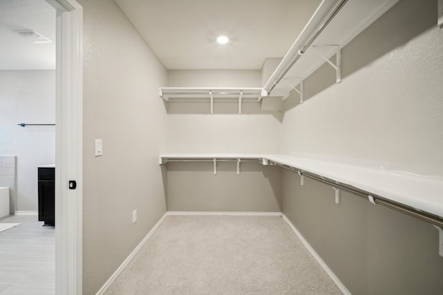 walk in closet featuring light colored carpet