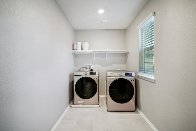 laundry area with washing machine and clothes dryer and light tile patterned floors