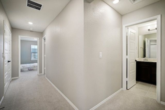 hallway with light colored carpet and sink