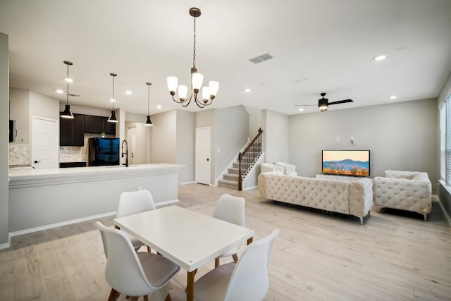 dining room featuring light hardwood / wood-style floors, sink, and ceiling fan with notable chandelier