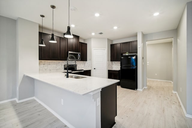 kitchen featuring light hardwood / wood-style flooring, hanging light fixtures, stainless steel appliances, backsplash, and kitchen peninsula