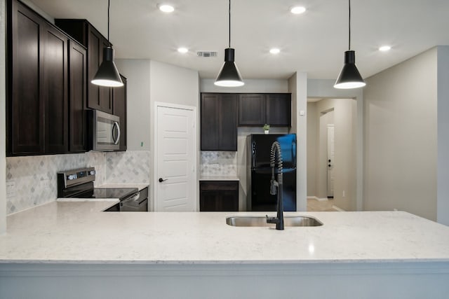 kitchen featuring hanging light fixtures, decorative backsplash, appliances with stainless steel finishes, and dark brown cabinetry