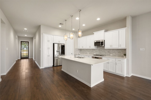 kitchen with tasteful backsplash, an island with sink, stainless steel appliances, light countertops, and a sink