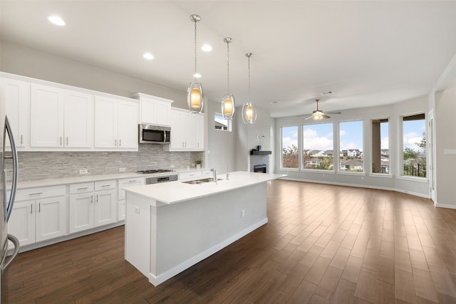 kitchen featuring a center island with sink, tasteful backsplash, light countertops, appliances with stainless steel finishes, and a sink