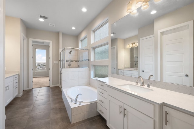 full bath with a stall shower, plenty of natural light, a garden tub, and vanity