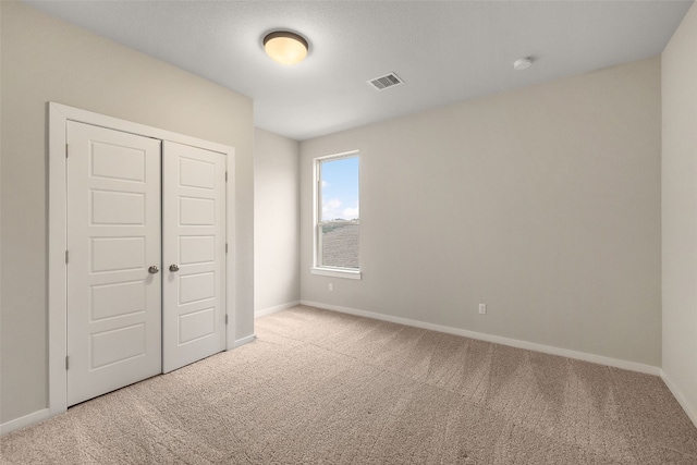 unfurnished bedroom featuring carpet, a closet, visible vents, and baseboards