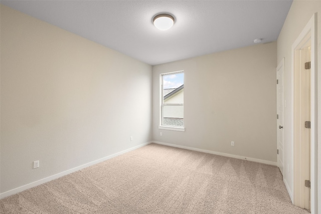 unfurnished room featuring light carpet and baseboards