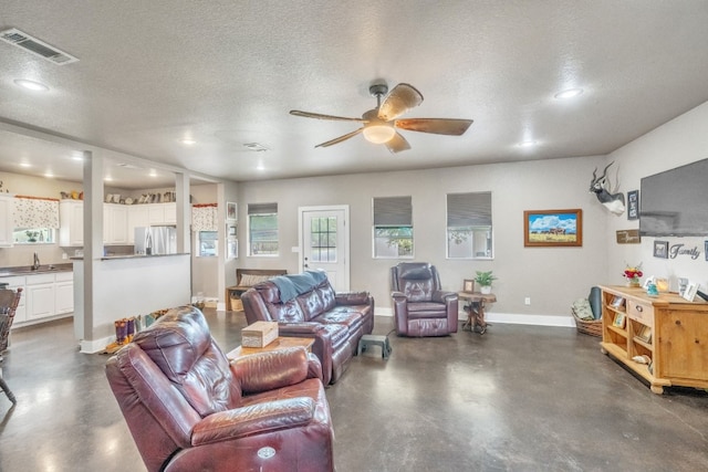 living room featuring ceiling fan and a textured ceiling