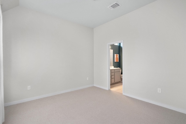 carpeted empty room with vaulted ceiling