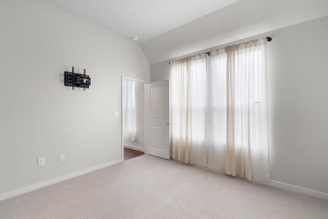 carpeted empty room featuring lofted ceiling