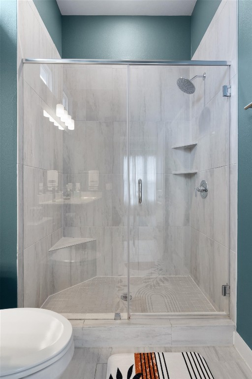 bathroom with toilet and an enclosed shower