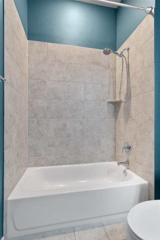 bathroom featuring tile patterned floors, toilet, and tiled shower / bath