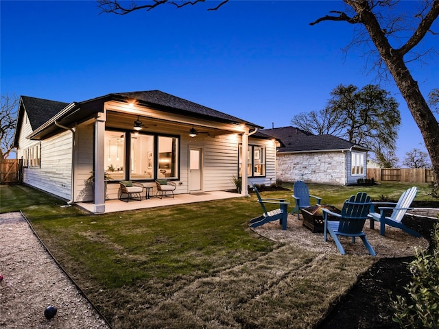 back house at dusk featuring an outdoor fire pit, ceiling fan, a yard, and a patio area