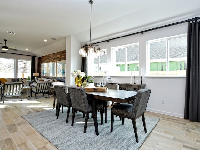 dining area featuring light wood-type flooring, ceiling fan with notable chandelier, and vaulted ceiling